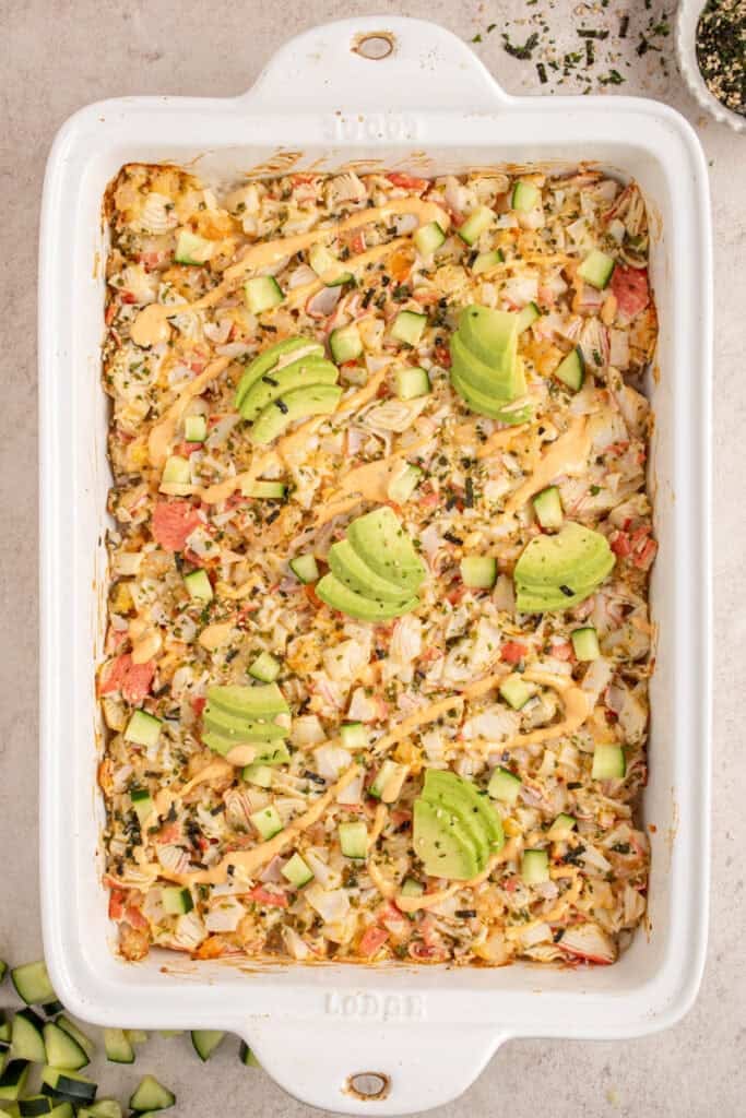 Adding the garnishes to the shrimp and crab sushi bake.