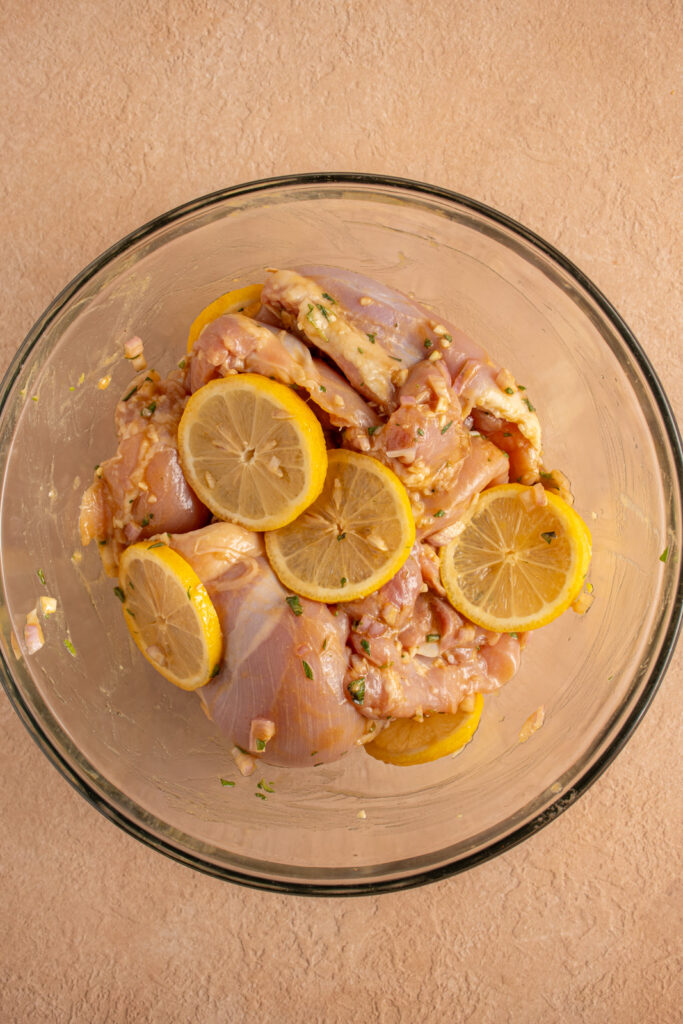 Raw lemon and chicken together in a marinade.