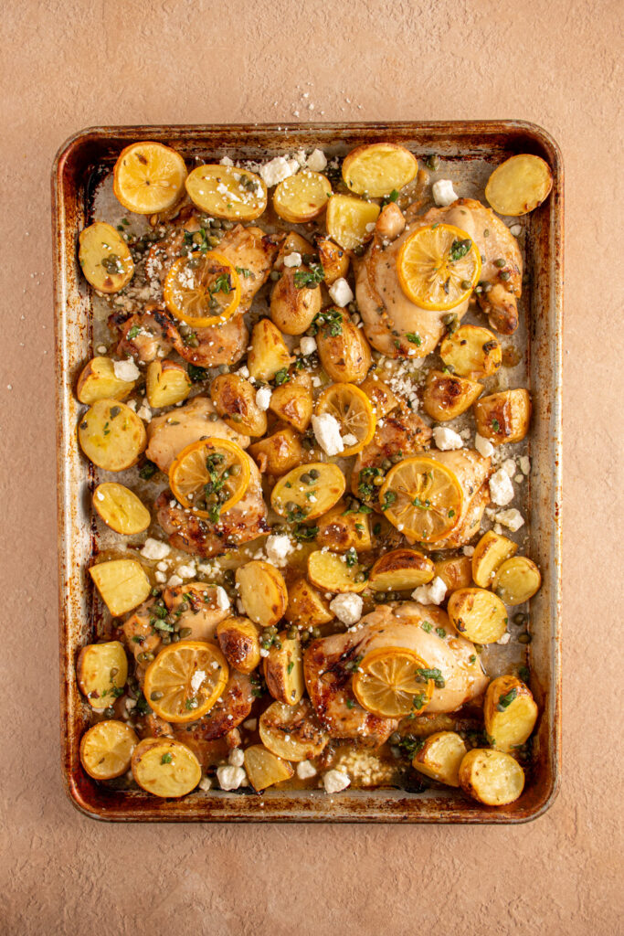 A sheet pan with balsamic chicken thighs, lemon, and potatoes.