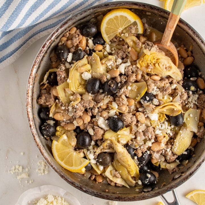 A skillet with ground turkey, black olives, beans, artichoke hearts, and feta cheese.