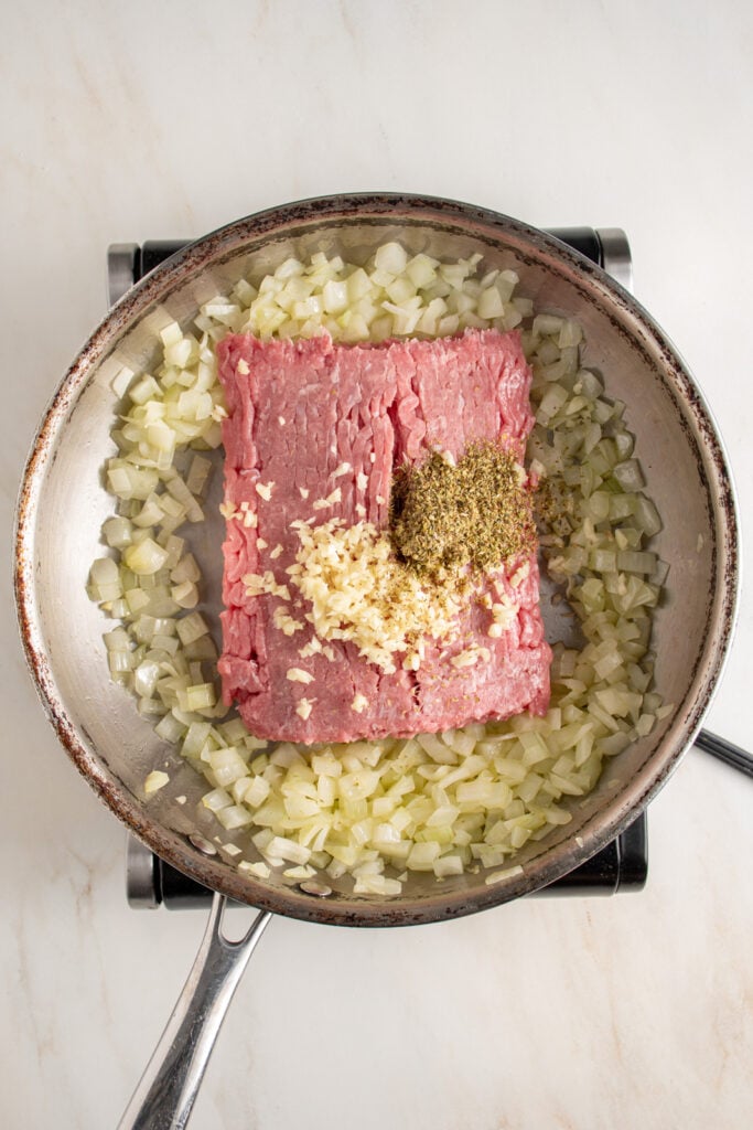 Ground turkey, garlic, and oregano added to a skillet.