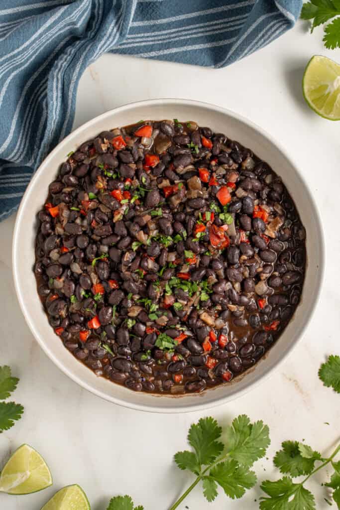 A large bowl with seasoned black beans garnished with cilantro.
