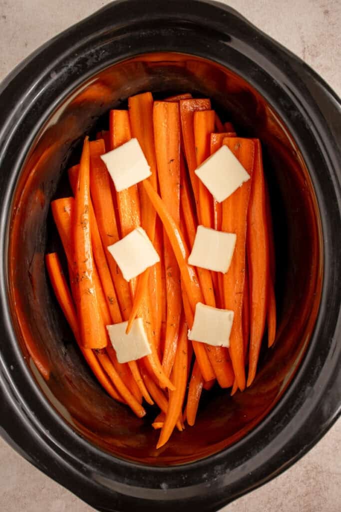 Raw carrots in a crockpot with butter.