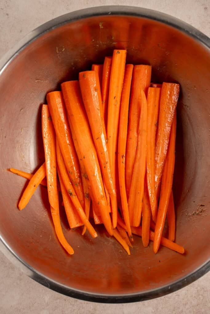 Seasoned carrots in a mixing bowl.
