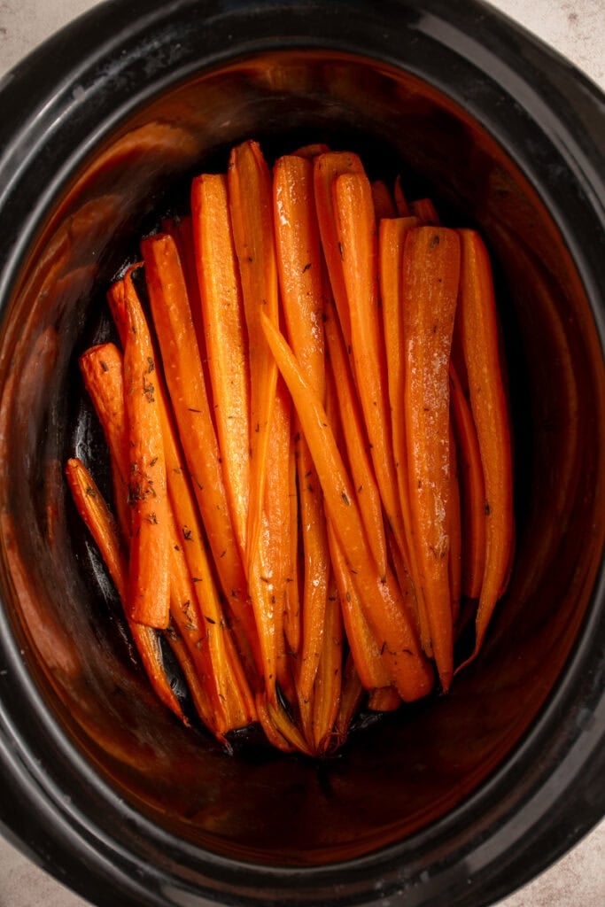 A black crockpot with cooked carrots.