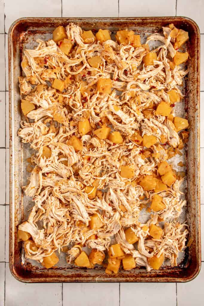 A sheet pan with shredded chicken and pineapples.