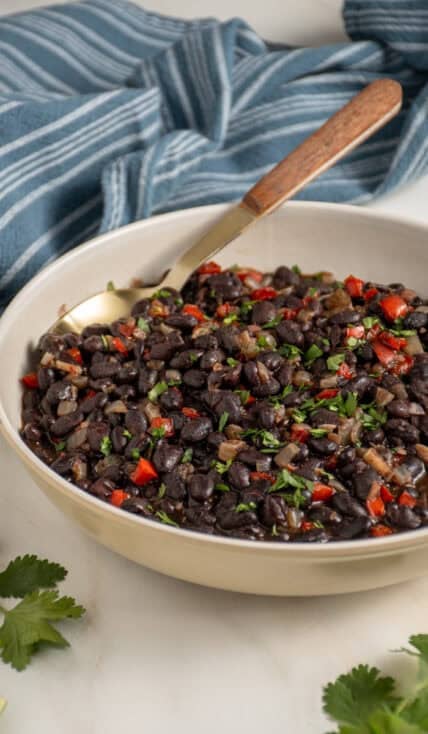 A large bowl with seasoned black beans garnished with cilantro.