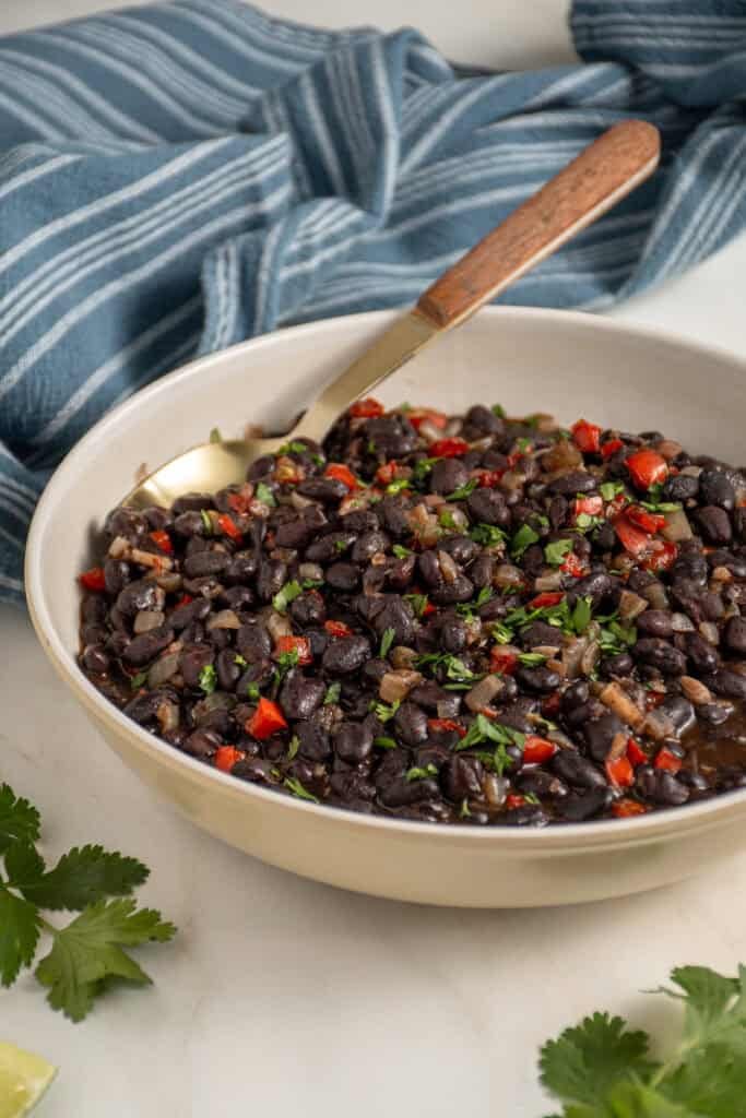 A large bowl with seasoned black beans garnished with cilantro.