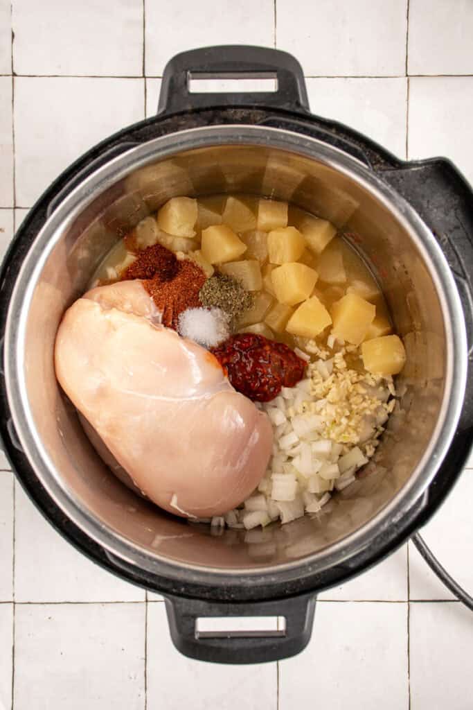 Ingredients for making pineapple chicken tacos in a pressure cooker pot.