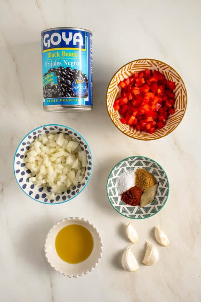 Ingredients to make seasoned canned black beans laid on a tabletop.