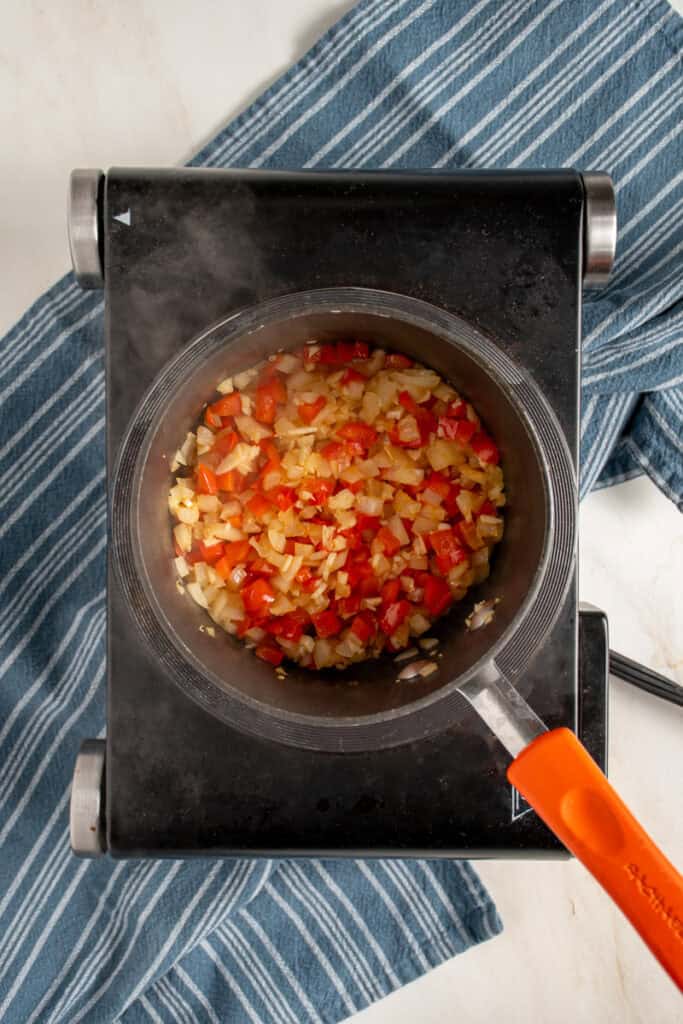 Sautéed peppers and onions in a small pot.