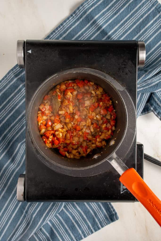 A small pot with seasoned onions and bell peppers.