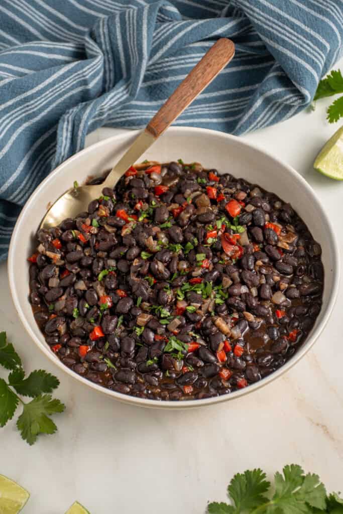 A large bowl with seasoned black beans garnished with cilantro.