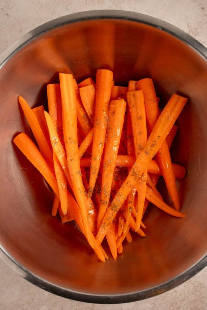Seasoned carrots in a mixing bowl.