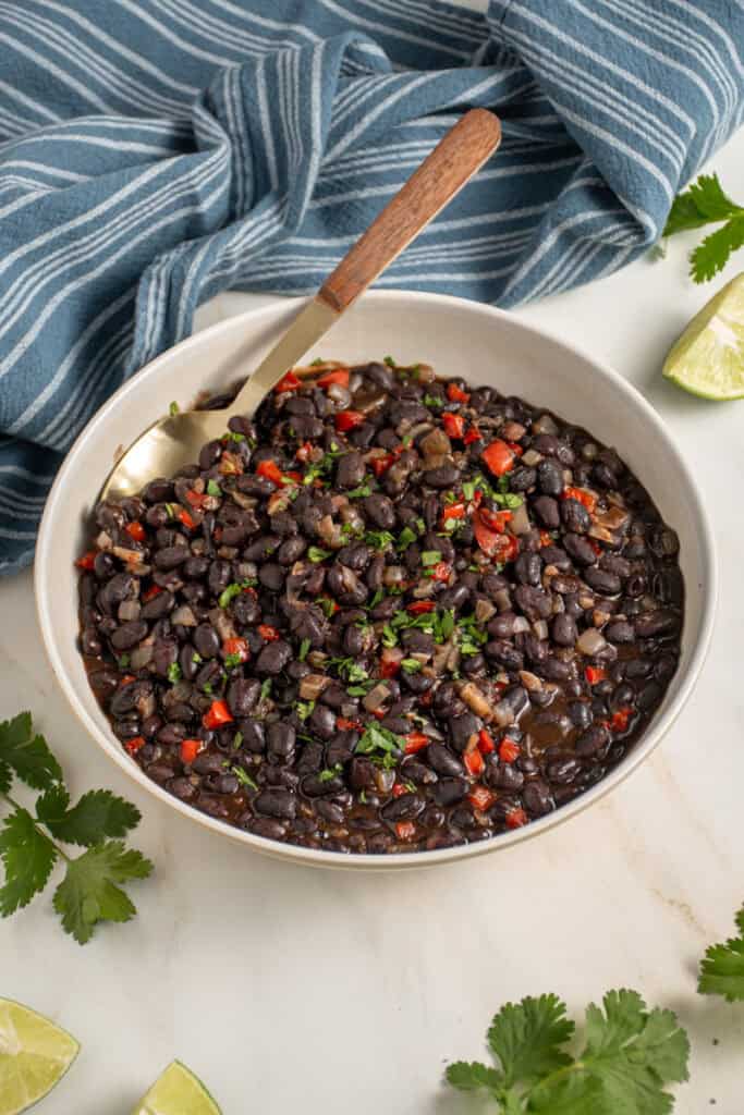 A large bowl with seasoned black beans garnished with cilantro.