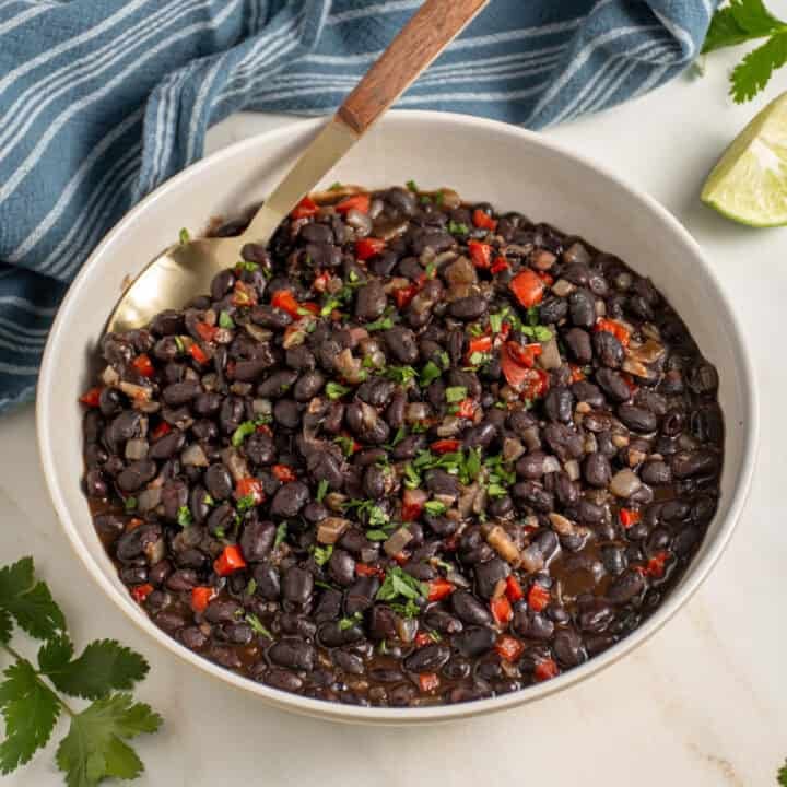A large bowl with seasoned black beans garnished with cilantro.