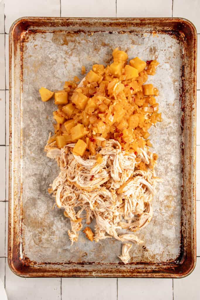 A sheet pan with shredded chicken and pineapple.