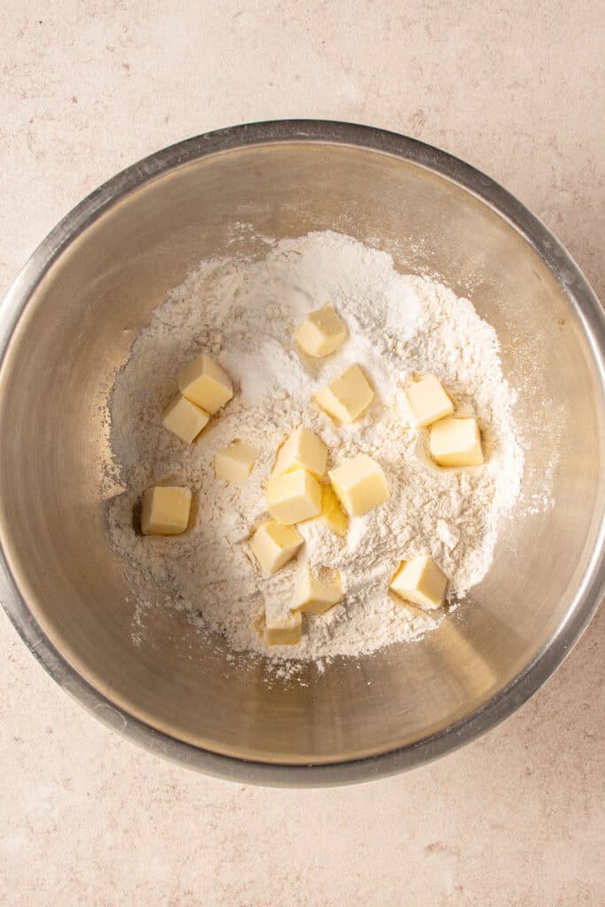 Cubes of butter being added to the dry biscuit ingredients.