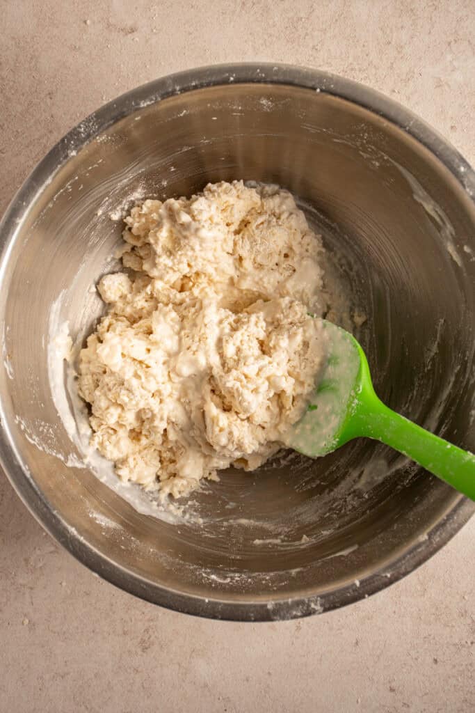 A rubber spatula mixing together the biscuit dough.