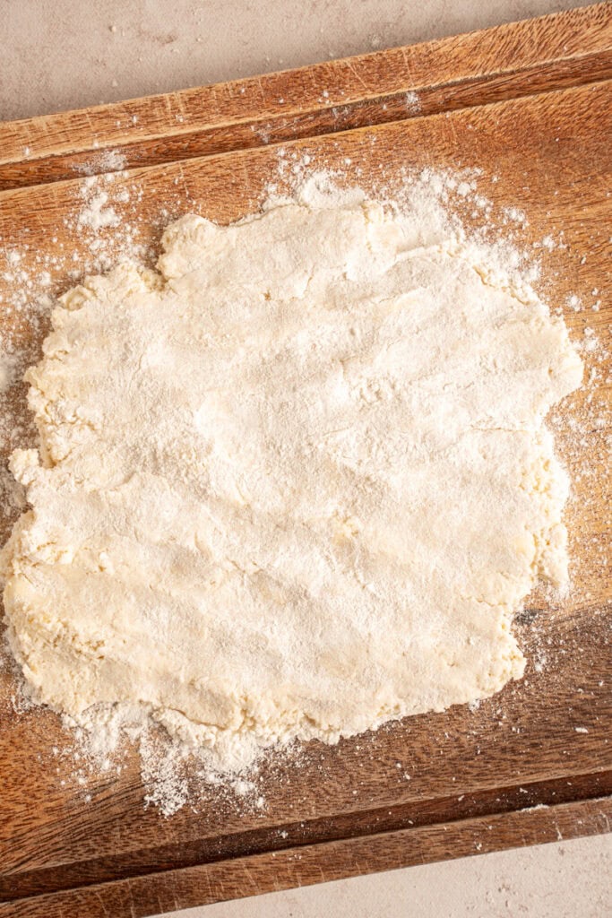 Flattened biscuit dough on a cutting board.