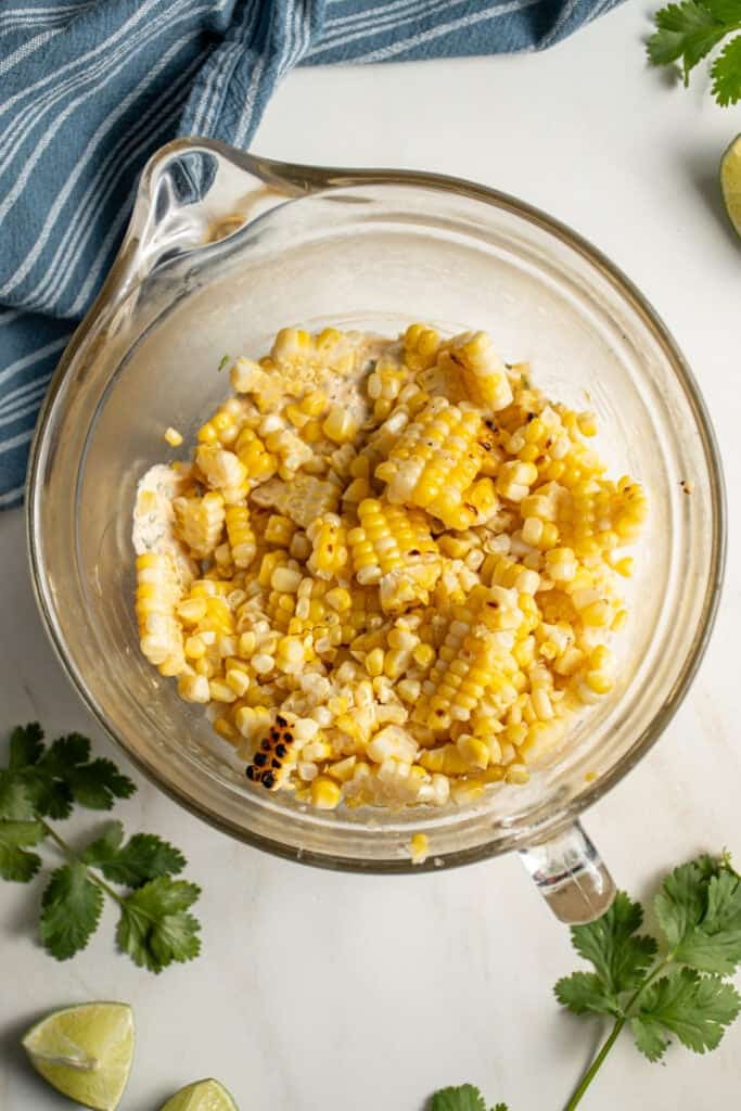 The corn being added to the dip base in a bowl.