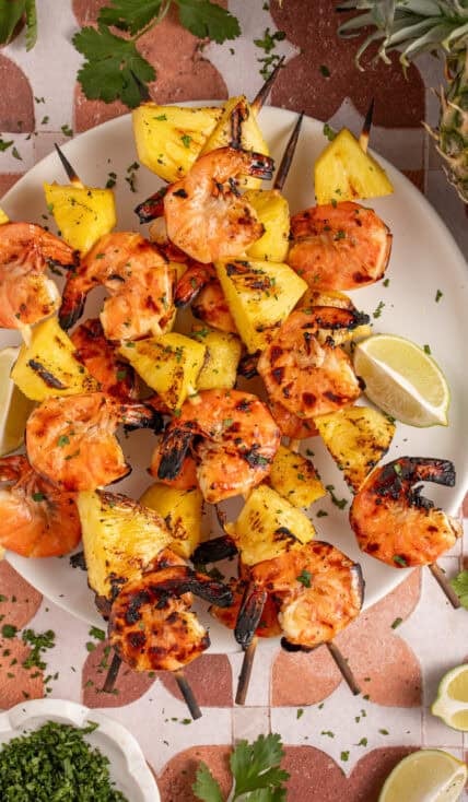 A plate with grilled pineapple shrimp skewers.