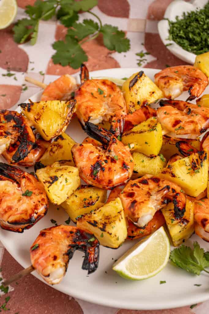A plate with grilled pineapple shrimp skewers.