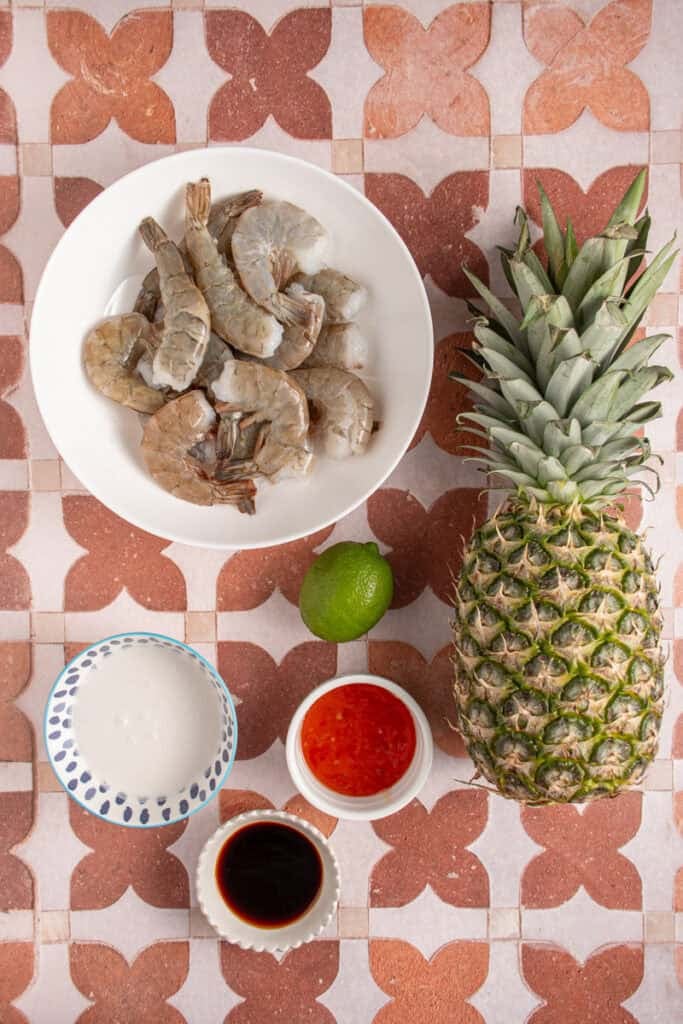 Ingredients to make pineapple shrimp skewers laid out on a tabletop.