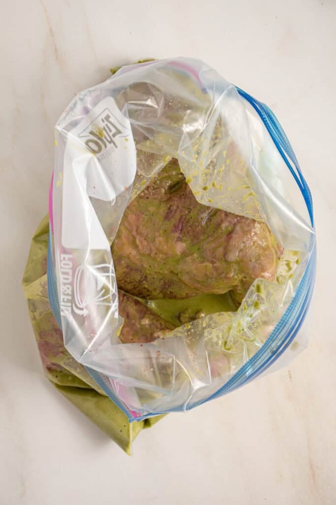 An open zip top bag with steak and marinade.