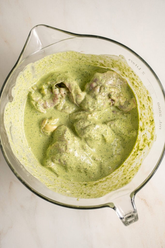 Boneless skinless chicken thighs marinating in green goddess dressing.