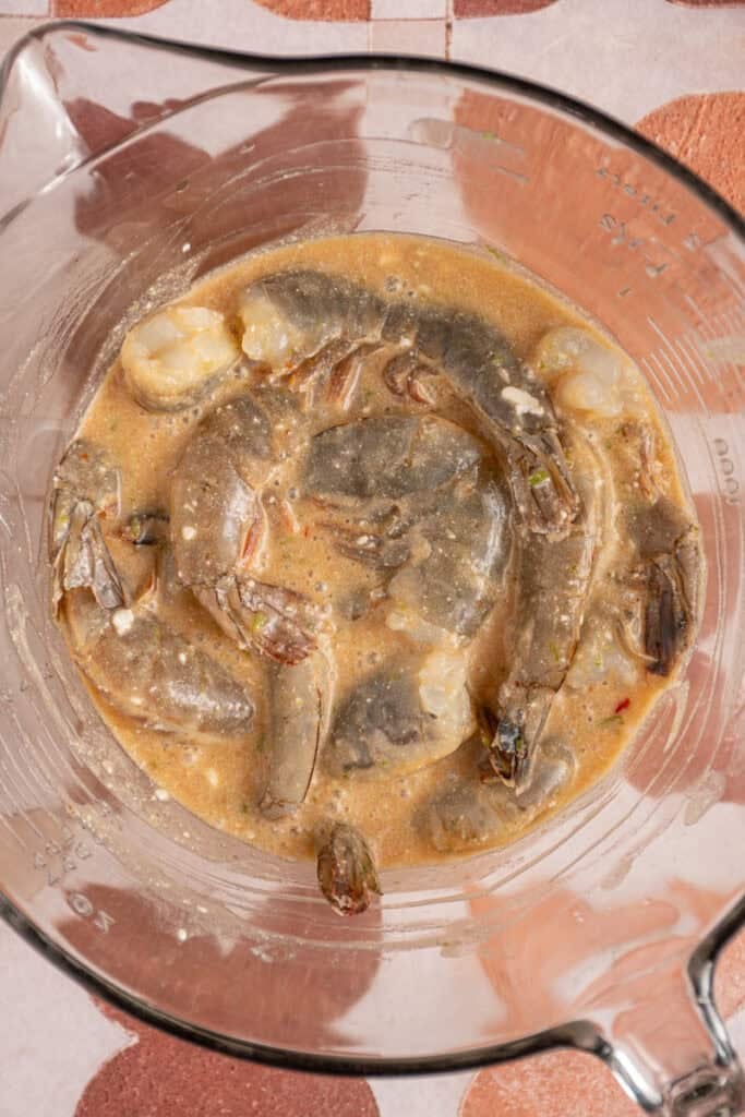 Shrimp marinating in a glass bowl.