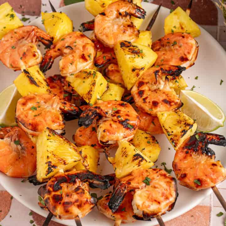 A plate with grilled pineapple shrimp skewers.