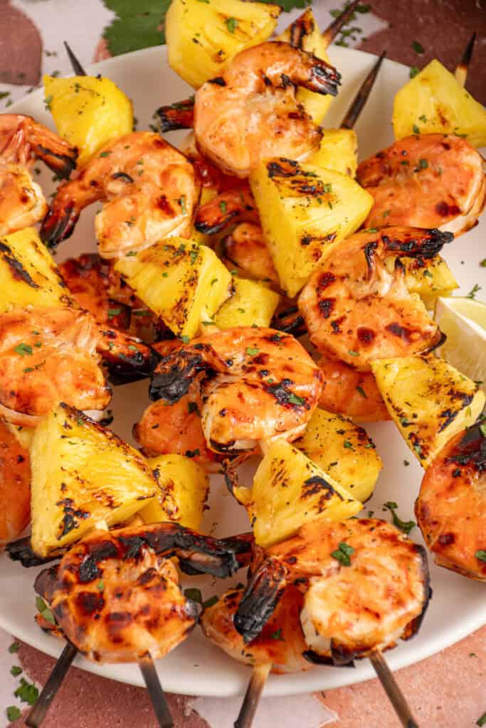 A plate with grilled pineapple shrimp skewers.