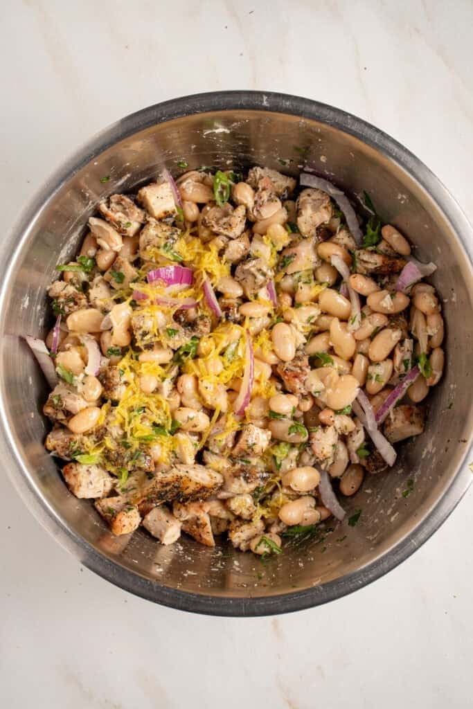 Adding lemon dressing to the dense white bean salad.