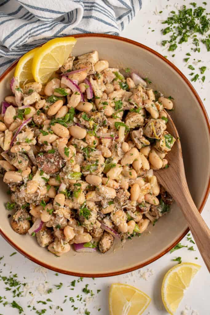 Bowl with dense white bean salad and grilled chicken garnished with parsley.