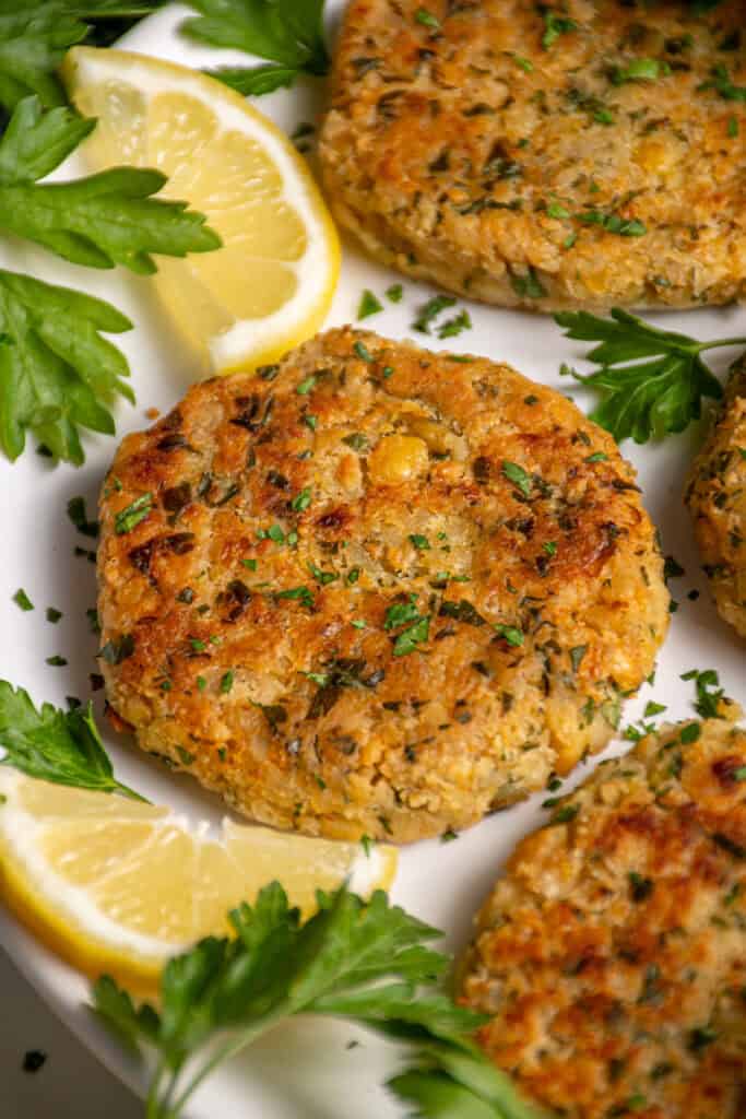 A plate with golden brown and crispy chickpea fritters, fresh parsley, and lemon slices.