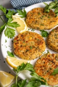 A plate with golden brown and crispy chickpea fritters, fresh parsley, and lemon slices.