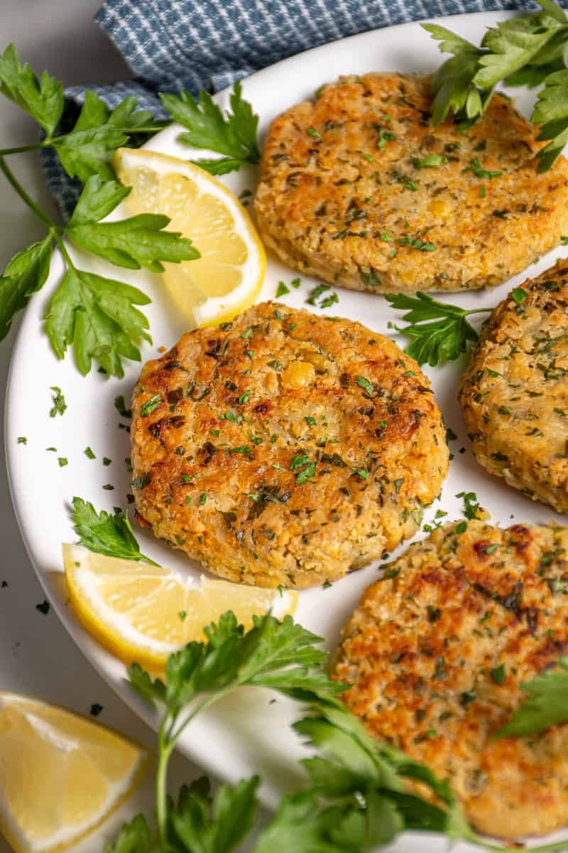 A plate with golden brown and crispy chickpea fritters, fresh parsley, and lemon slices.