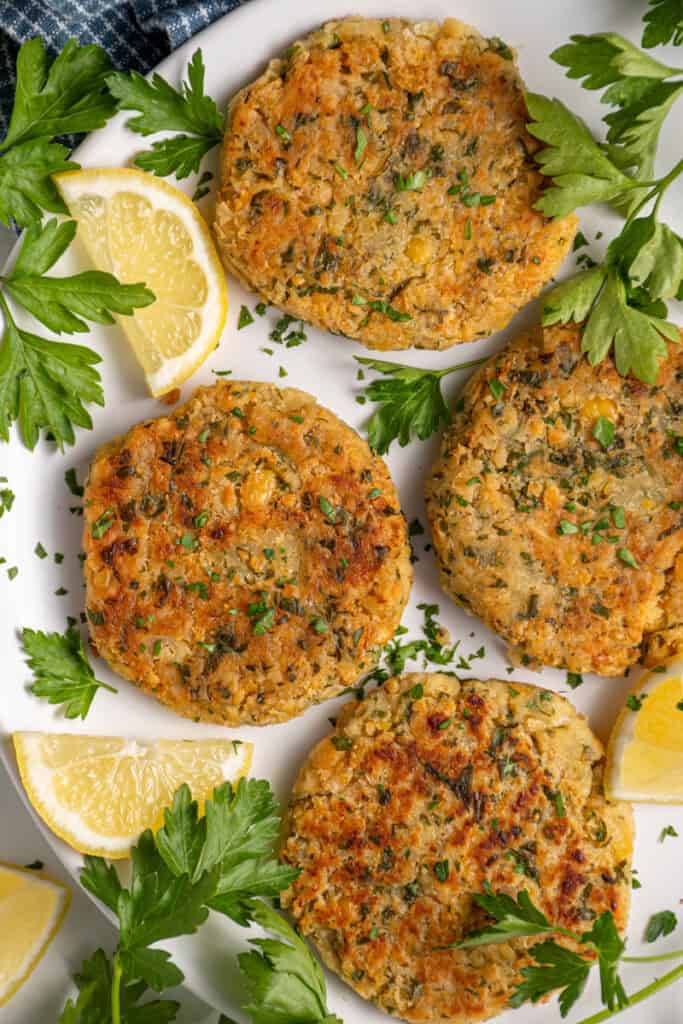 A plate with golden brown and crispy chickpea fritters, fresh parsley, and lemon slices.