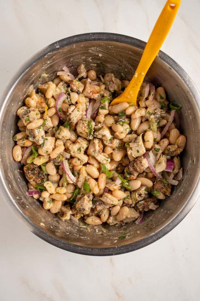 Bowl with dense white bean salad and grilled chicken.