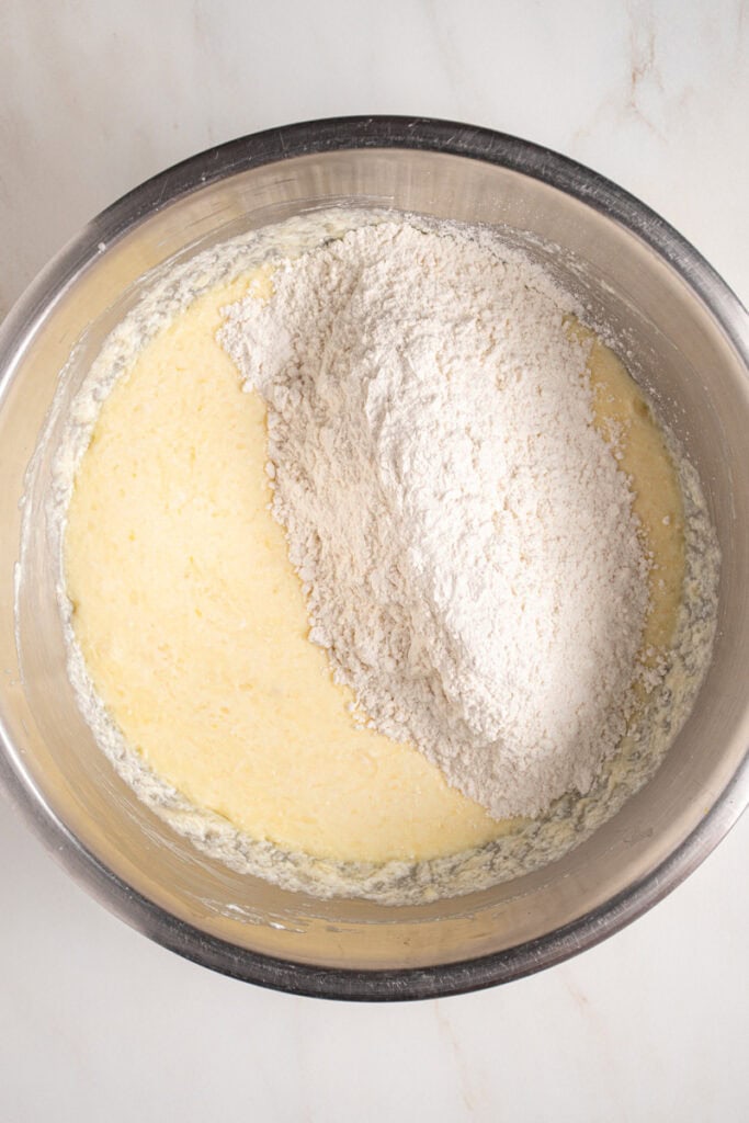 Dry ingredients being added to wet ingredients in a bowl.