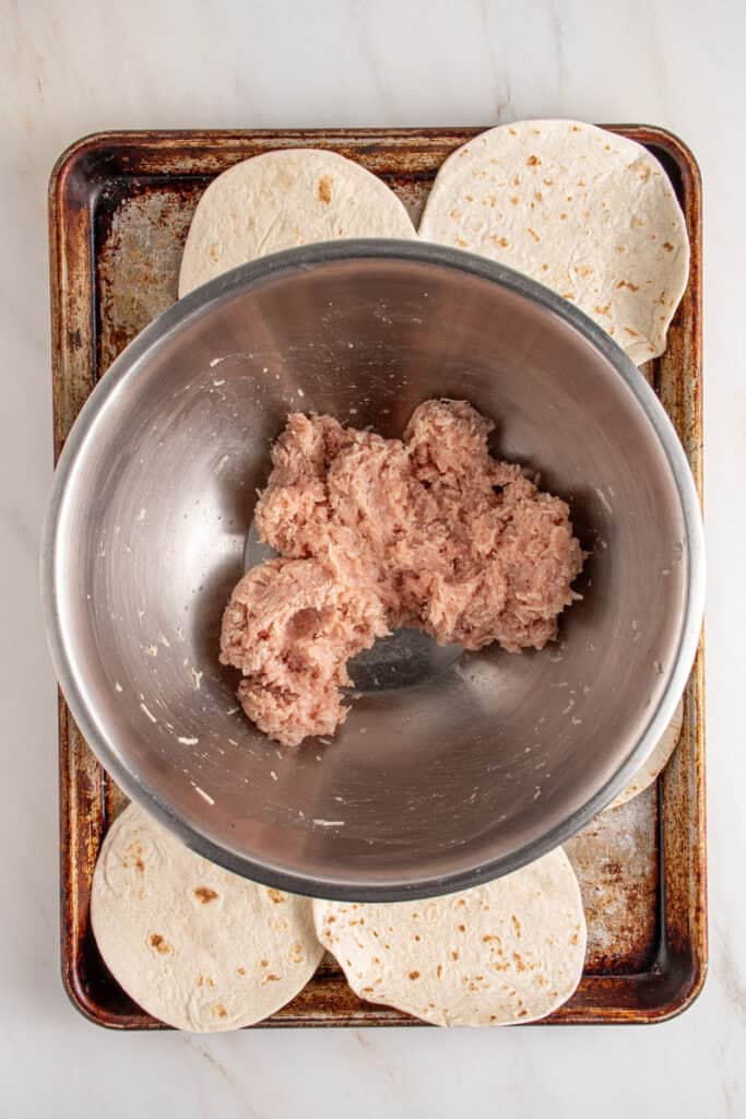Ground chicken in a bowl mixed with parmesan cheese.
