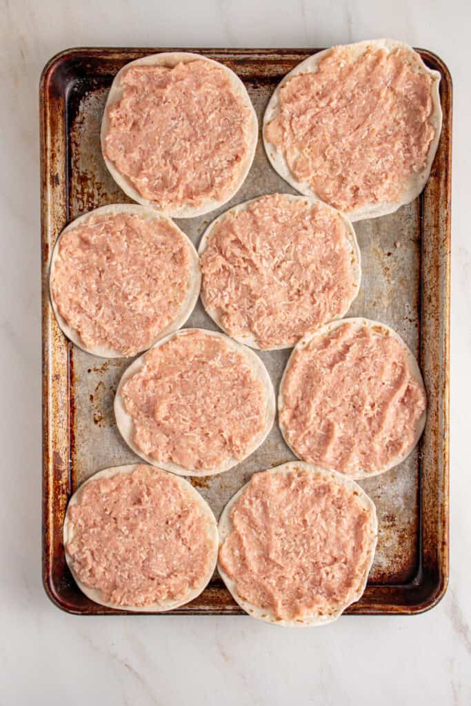 Ground chicken smashed onto flour tortillas.