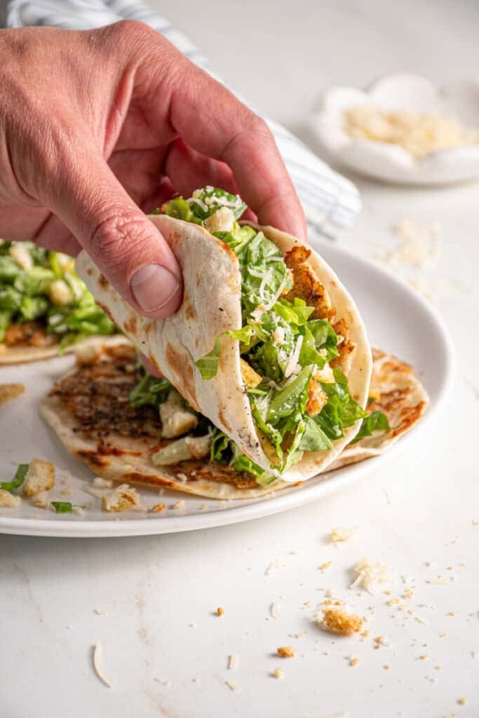 A hand holding a chicken caesar smash taco.