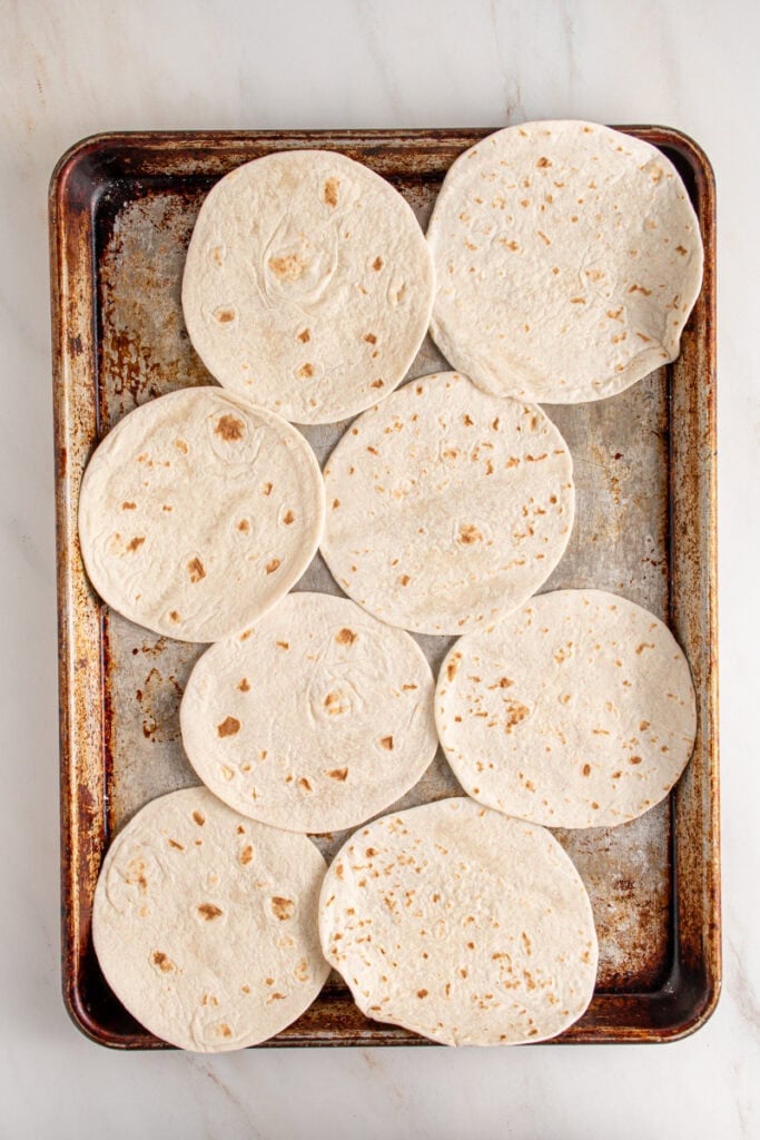 Small flour tortillas on a sheet pan.