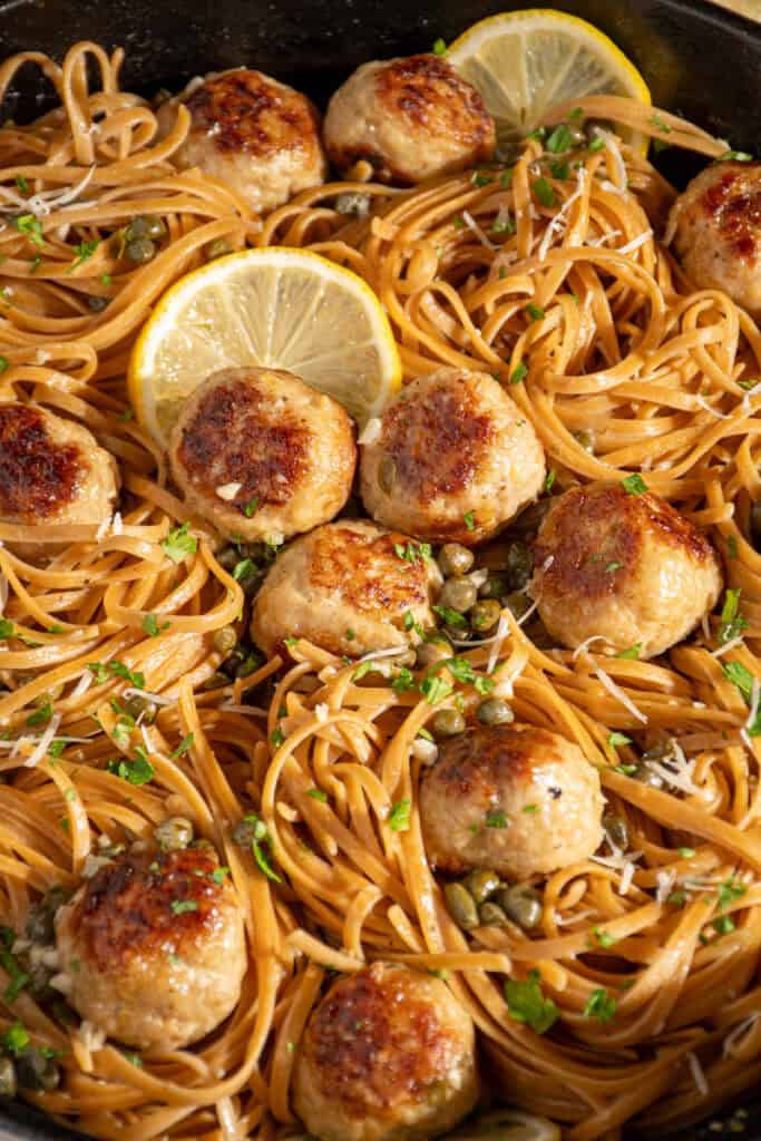 A skillet full of pasta and chicken piccata meatballs.
