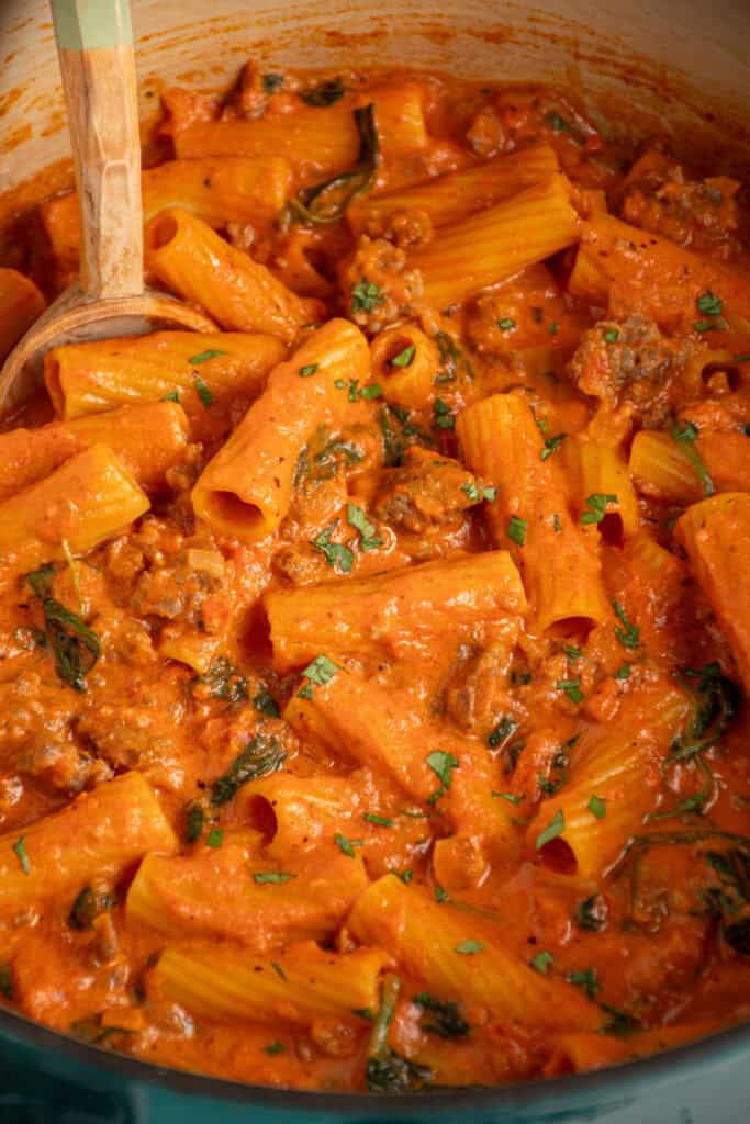A dutch oven filled with Creamy One Pot Sausage Rigatoni.