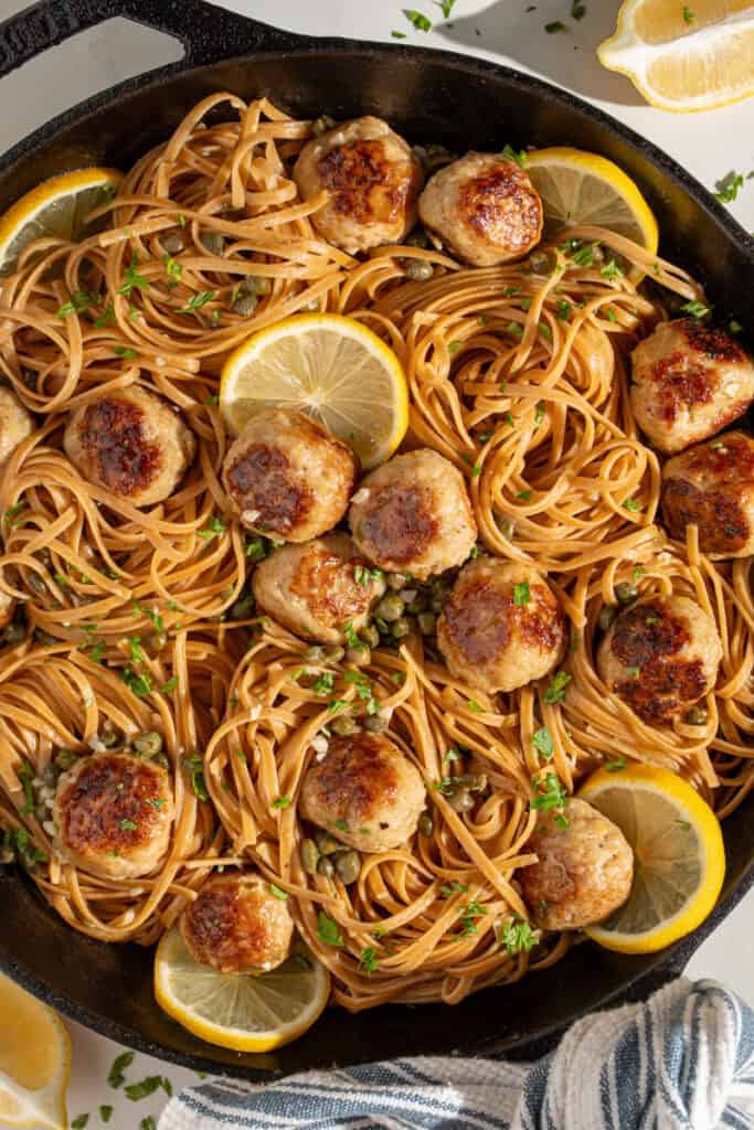 A skillet full of pasta and chicken piccata meatballs.