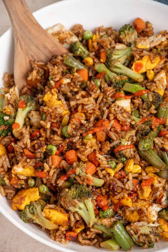 A large white bowl filled with frozen veggie fried rice drizzled with sriracha.