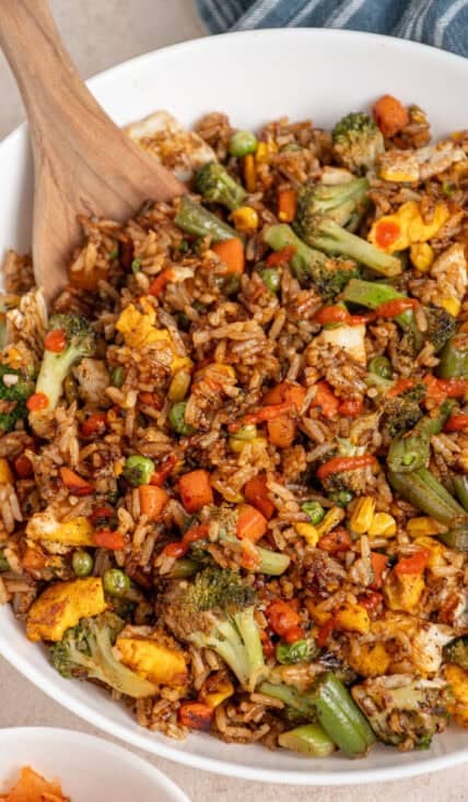 A large white bowl filled with frozen veggie fried rice drizzled with sriracha.